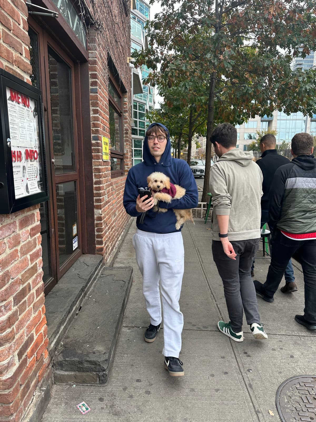 Luke carrying puppy Luna in his arms on a Brooklyn sidewalk